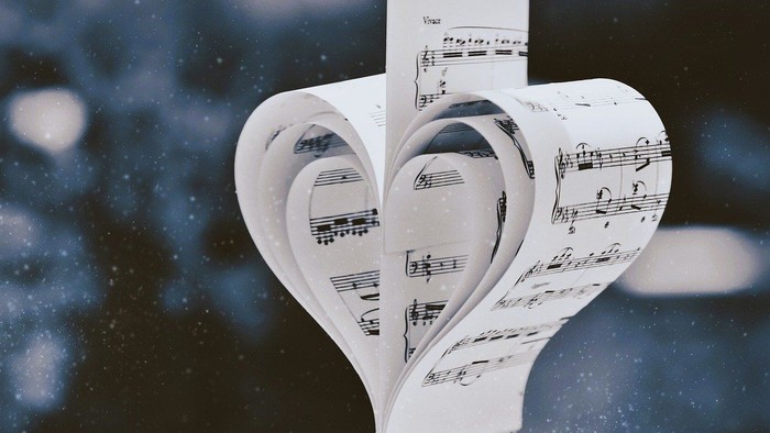 Et hjerteformet papirudklip med noter, hængende i sne.