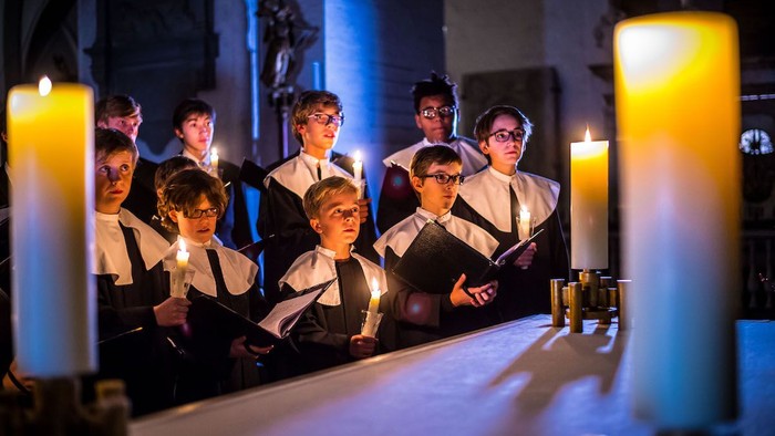 Jungen der Lübecker Knabenkantorei singen im Kerzenschein und mit Kerzen in der Hand im Dom zu Lübeck.