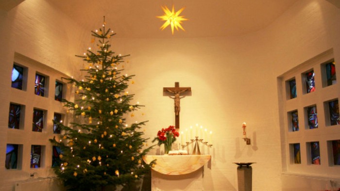 Weihnachtsdekoration in Kirche mit Christbaum und Kreuz