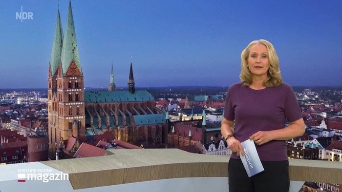 Frau berichtet vor historischer europäischer Stadtkulisse mit hohen Kirchtürmen.