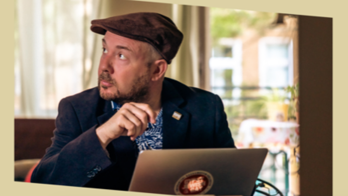 Mann im Anzug und mit Hut arbeitet am Laptop.