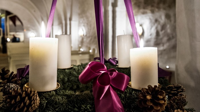 En adventskranse med fire lysende lygter og rød bændel.