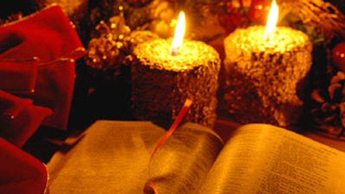 En åben bog med lysende lys og røde blomster