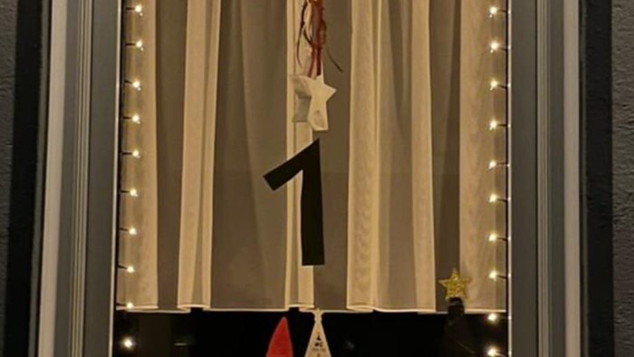 Ein Schaufenster mit Weihnachtsdekoration, darunter eine Figur und eine beleuchtete Vorhangszene