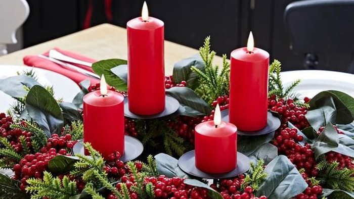 Christmas centerpiece with red candles and berries on dining table
