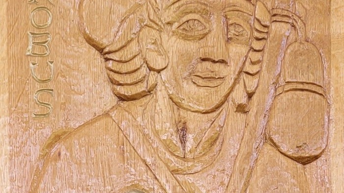 Das Relief zeigt eine geschnitzte Figur mit Hut und Instrument.