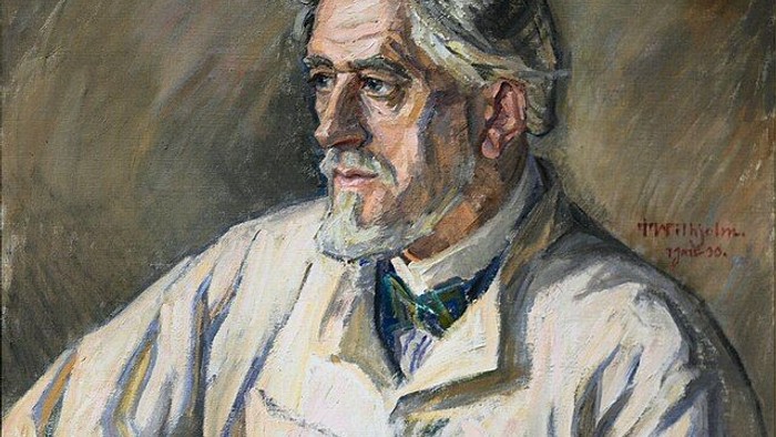 Portræt af en ældre mand med briller og skæg, iført hvid skjorte og slips.