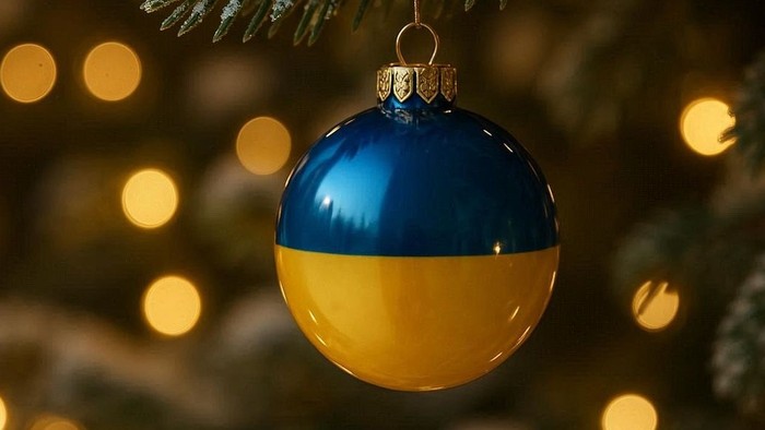 Eine blau-gelbe Weihnachtskugel hängt an einem Tannenbaum.