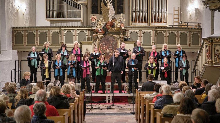 Ein gemischter Chor mit mehrfarbigen Schals vor dem Altar einer historischen Kirche