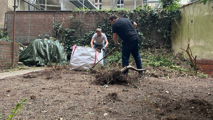 Zwei Männer bearbeiten den Boden in einem Garten und bereiten ihn für das Anpflanzen vor