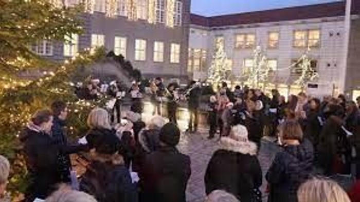 En gruppe af mennesker står udenfor et stort hus og taler med hinanden.