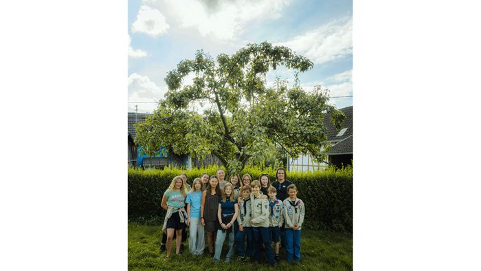 Gruppe von Menschen, die unter einem großen Baum im Freien posieren