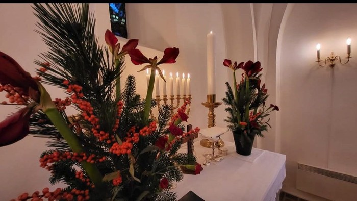 Kirkealter med stearinlys, blomster og religiøse symboler