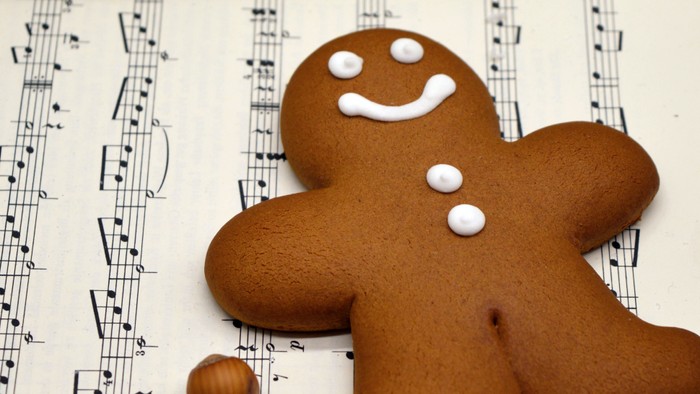 Lebkuchenmann-Plätzchen mit Haselnüssen auf Notenblättern.