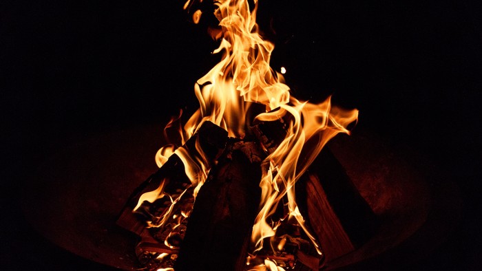 Ein Lagerfeuer brennt hell in der Dunkelheit.