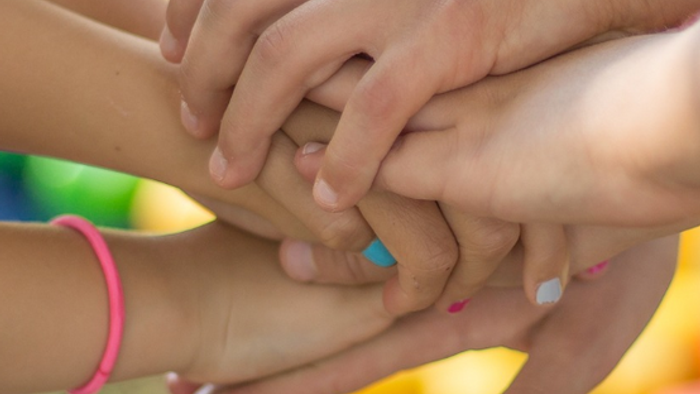 Viele Hände bilden einen Stapel, Symbol für Teamgeist und Zusammenhalt