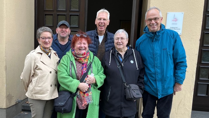 Gruppe von sechs Personen, die draußen vor einem Gebäude posieren.