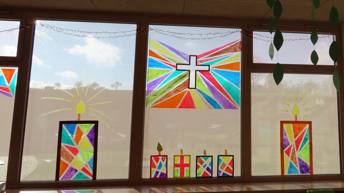 Klassenzimmer mit religiös thematisierten Buntglasfenstern und Dekorationen