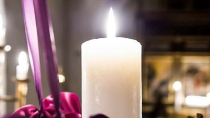 En lysende lyse med lilla bånd og gran.