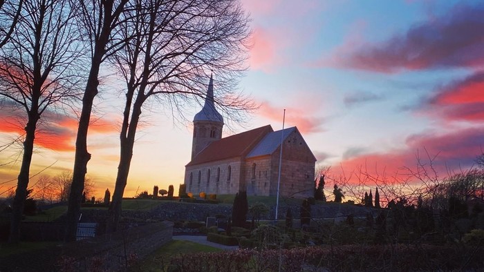 En kirke på en bakke ved solnedgang