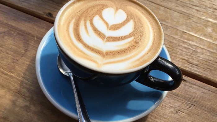 Eine Tasse Kaffee mit Milchschaumherz auf einem Holztisch