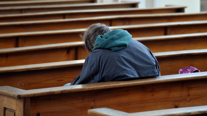 Jemand sitzt in einer Kirchenbank und betet