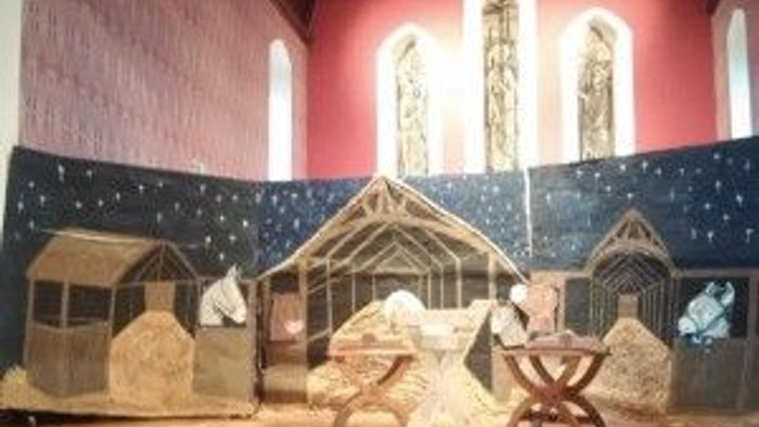 Nativity scene displayed inside a church with stained glass windows.