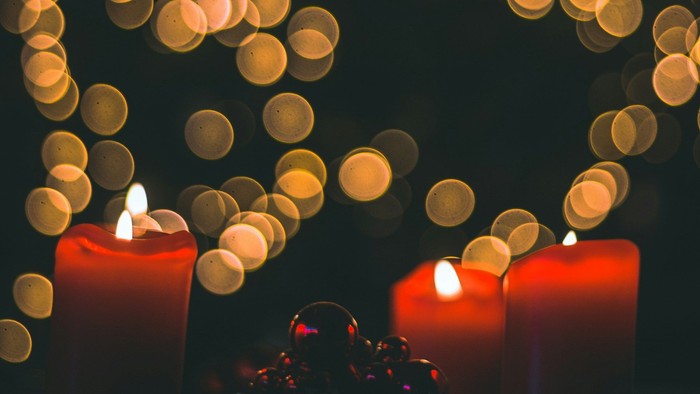Vier rote Kerzen vor einem dunklen Hintergrund mit vielen Lichtpunkten