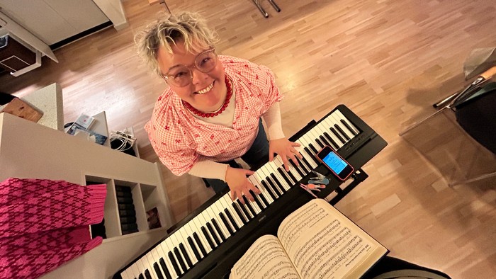 Kvinde, der spiller keyboard med en åben bog foran sig.