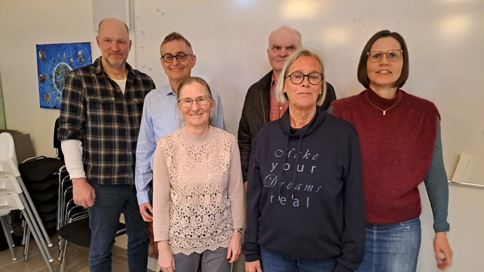 En gruppe af seks personer står sammen i et rum.