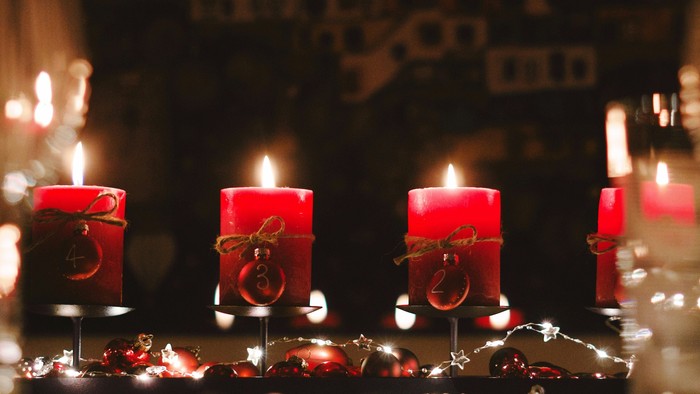 Firelyder i røde lysestake på bord.