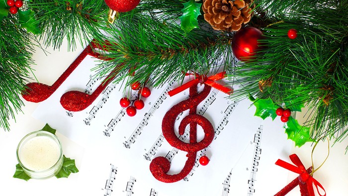 En festlig dekoration med grønne nåler, røde glitrende kugler og musiknoter til jul