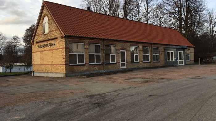 En lille, nyopført hus med rødt tag og flere vinduer, placeret i en tomt og øde område.