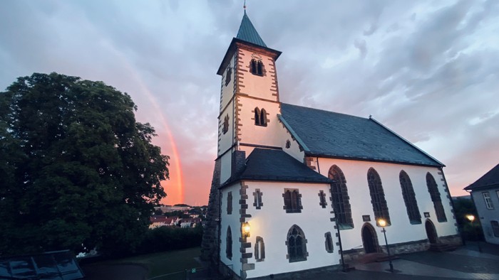Kirchengebäude bei Sonnenuntergang mit Regenbogen