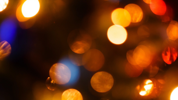 Unscharfe, bunte Lichter in verschiedenen Gelb-, Orange- und Blautönen, die eine festliche Atmosphäre schaffen.
