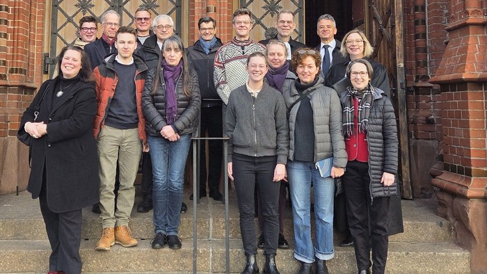 Ein Gruppenfoto von Männern und Frauen vor dem Eingang einer Kirche