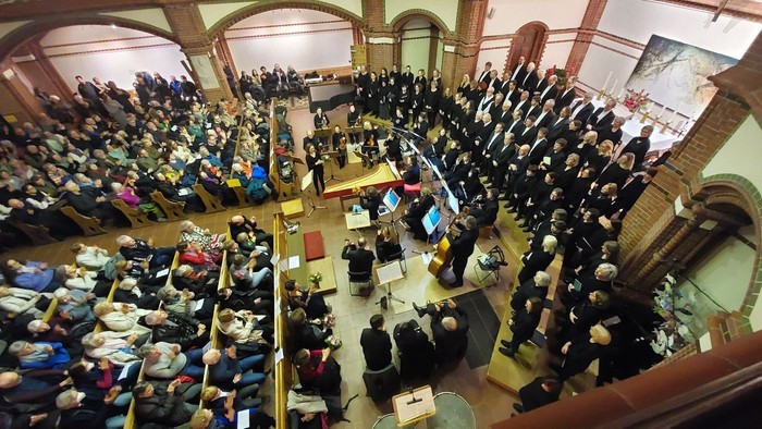 Ein großer Chor, ein Orchester, Musiker und Sänger in einer voll besetzten Kirche
