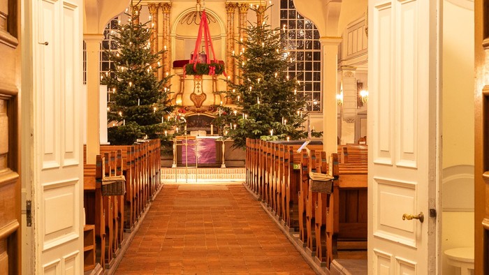 Weihnachtsbäume und Dekorationen in einem Raum mit einem Bogenportal