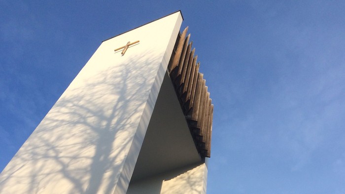 Ein modernes Gebäude mit einem goldenen Logo vor einem klaren blauen Himmel