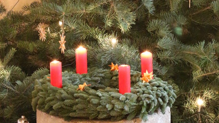 Weihnachtsdekoration mit vier brennenden Kerzen und Tannenzweigen