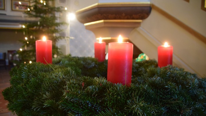 Vier Kerzen am Adventskranz, dahinter der Weihnachtsbaum in der Christuskirche Groß Köris