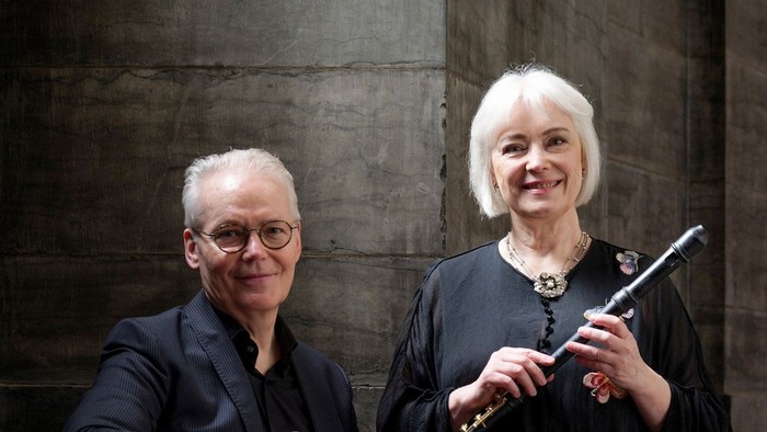En mand og en kvinde poser sammen, kvinden holder en fløjte.