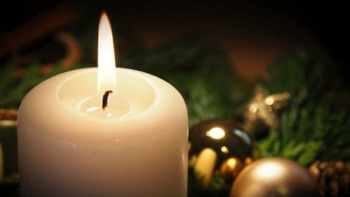 Weihnachtliche Szene mit brennender Kerze und Christbaumkugeln