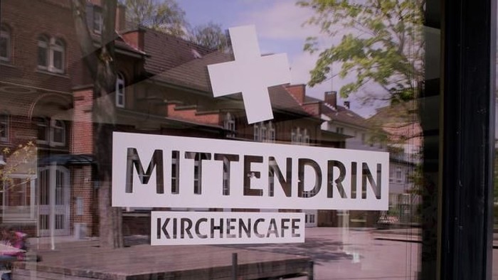 Durch die Glastür ist das Schild der Kirchencafé Mittendrin zu sehen