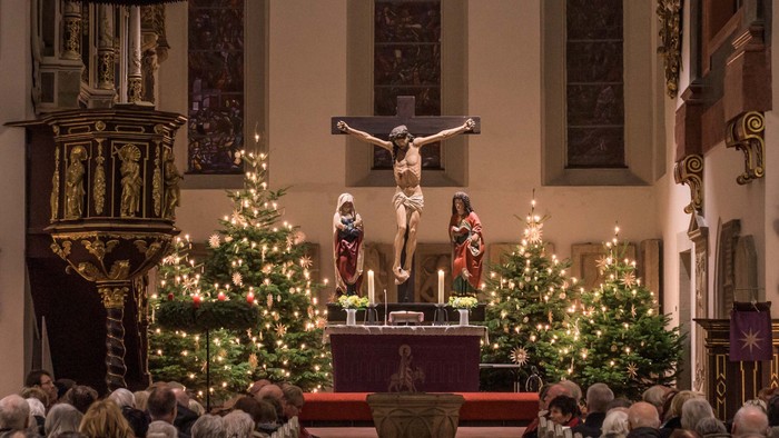 Ein Blick in die mit Weihnachtsbäumen festlich geschmückte Georgenkirche mit dem Stern über dem Altar