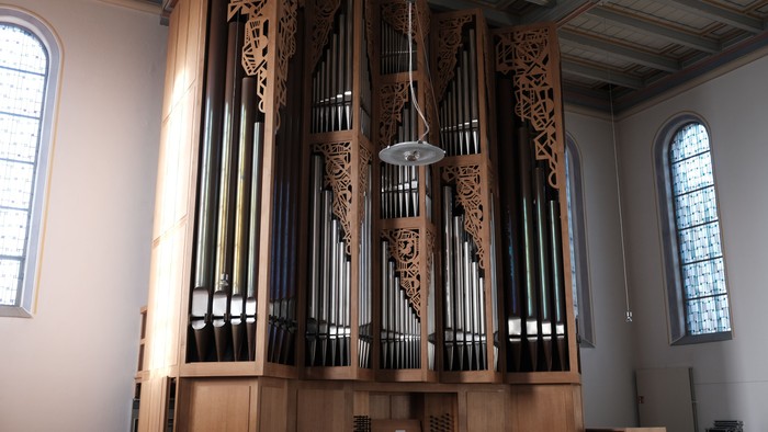 Große Kirchenorgel mit filigranem Holzschnitzwerk in einem hellen Raum