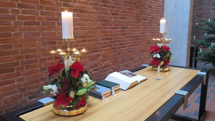 Bord med blomsterarrangementer og lysstake mod rød mursten