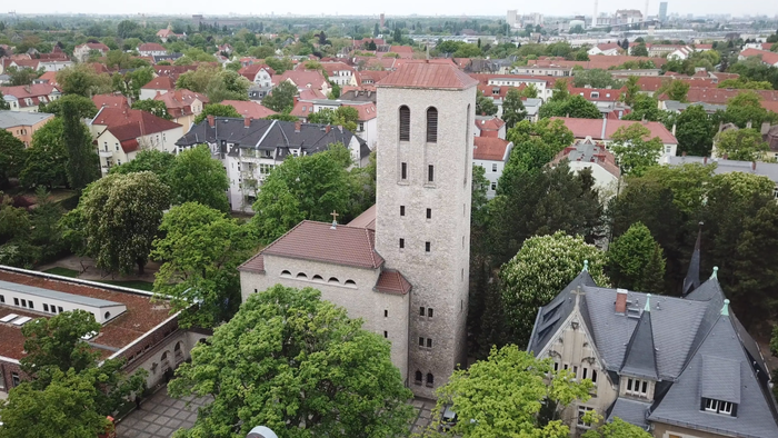 Die Stadtansicht zeigt eine Kirche mit hohem Turm und umgebende Häuser.