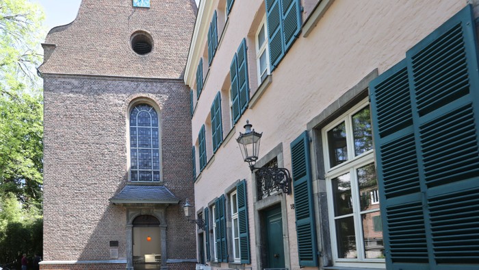 Das Bild zeigt einen historical Gebäude mit einem Glockenturm und grünen Fensterläden.
