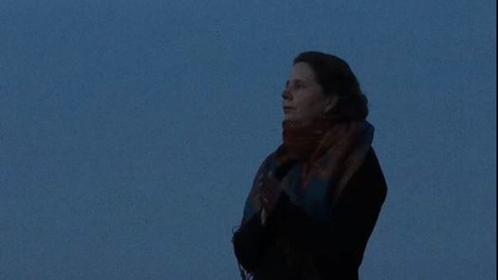 Eine Person mit gefalteten Händen steht als Silhouette vor einem dämmrigen Himmel.